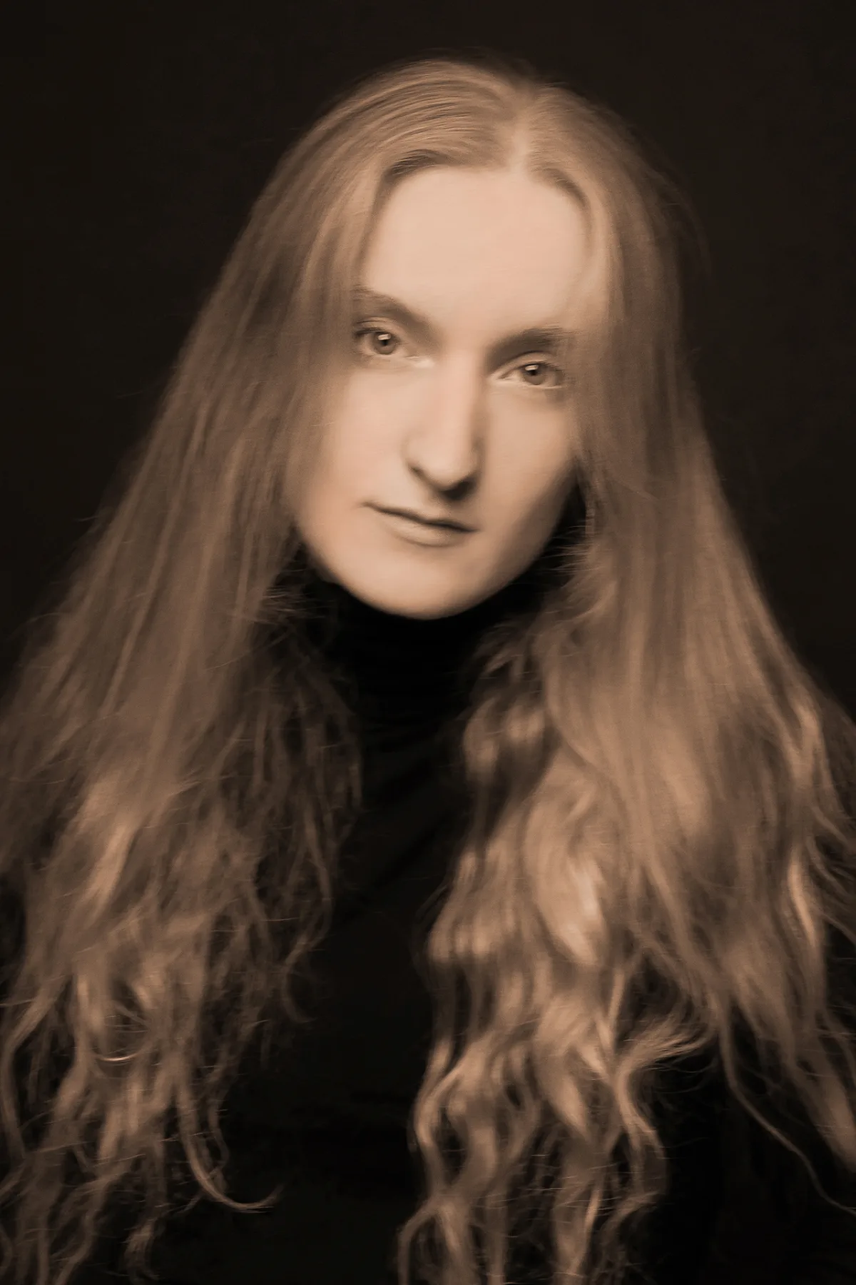 Sepia beauty portrait of a young woman with long wavy hair, soft studio look
